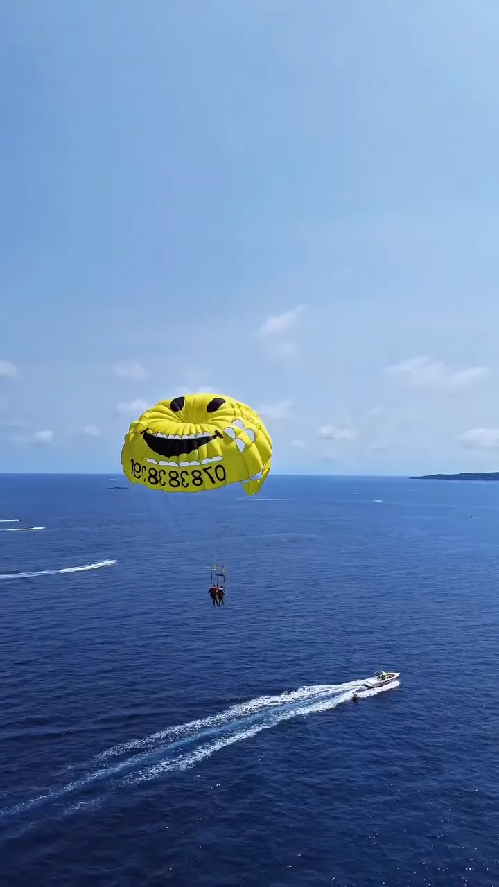 Parachute ascensionnel jaune en forme de smiley au-dessus de la mer du golfe